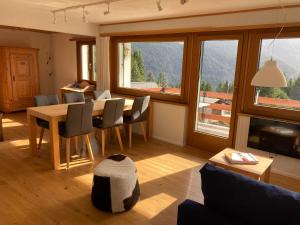 - un salon avec une table, des chaises et des fenêtres dans l'établissement Haus Tgamotsch***- Ferienwohnung in Valbella, à Valbella