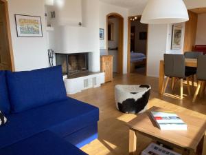 ein Wohnzimmer mit einem blauen Sofa und einem Tisch in der Unterkunft Haus Tgamotsch***- Ferienwohnung in Valbella in Valbella