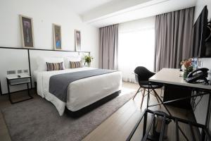 a bedroom with a large white bed and a desk at Sarova Imperial Hotel in Kisumu