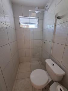 a white bathroom with a toilet and a window at Maria Farinha casa in Maria Farinha