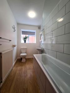 een badkamer met een bad, een toilet en een raam bij The North Bay Hideaway, Scarborough in Scarborough