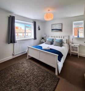 a bedroom with a bed with a blue blanket and two windows at The North Bay Hideaway, Scarborough in Scarborough