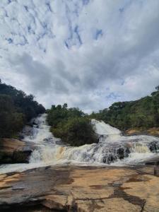 una cascada junto a un río con árboles en Cachoeira dos Luis - Parque & Pousada en Bueno Brandão