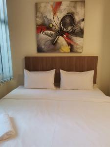 1 cama con 2 almohadas y una pintura en la pared en SCC Hotel Chinatown en Kuala Lumpur