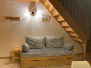 un canapé assis dans une pièce avec un escalier dans l'établissement GITE LE SOLAN DE FINE, à Saint-Jean-de-Belleville