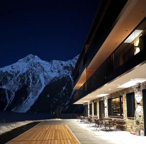 a building with tables and chairs in front of a mountain at Nativo Bergaparts in Längenfeld