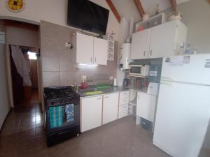 eine Küche mit weißen Schränken, einem Herd und einem Kühlschrank in der Unterkunft Resiliencia in Río Gallegos