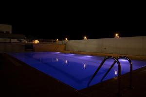 uma piscina à noite com iluminação azul em AL shoroq Green Resort em Ghubrat Ţanūf