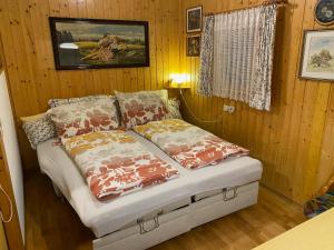 uma cama num quarto com paredes de madeira e uma janela em Troadkastn Familie Fritz em Passail