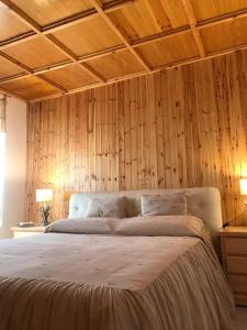 a bedroom with a large bed with wooden walls at Accogliente casa con camino in stile montano in Rovere