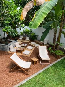 a patio with lounge chairs and tables and a palm tree at Jungle Villa in Ahangama