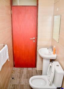 a bathroom with a red door and a toilet and a sink at Rhezoh Apartment in Nairobi