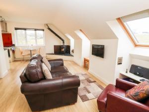 a living room with a leather couch and a tv at Tyn-y-Mynydd Bach in Halkyn