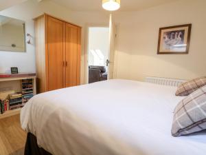a bedroom with a large white bed and a cabinet at Tyn-y-Mynydd Bach in Halkyn