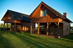 a large wooden house sitting on top of a lush green field at Orla Chata Baltic House in Świnoujście
