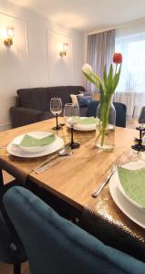 een houten tafel met borden en wijnglazen erop bij CentroPark Apartament in Olsztyn