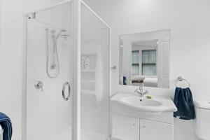 une salle de bain blanche avec lavabo et douche dans l'établissement Gold Rush Cottage - Arrowtown Holiday Home, à Arrowtown