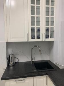 a kitchen counter with a sink and white cabinets at Jurata Apartament Glamour in Jurata