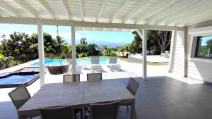 une salle à manger avec une table et des chaises sur une terrasse dans l'établissement VILLA ELA - Jolie villa avec piscine chauffée et jacuzzi, à Les Abymes