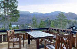 a wooden table and chairs on a deck with mountains at 3 Bedroom Lovely Home In Straumgjerde in Brunstad