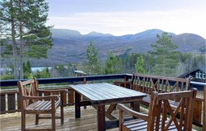 a wooden table and chairs on a deck with mountains at Beautiful Home In Straumgjerde With 3 Bedrooms in Brunstad