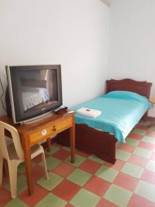 a bedroom with a tv and a table with a bed at Casa Bethlen in Zapatoca
