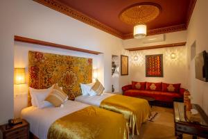 um quarto de hotel com duas camas e um sofá em Riad les remparts de la kasbah em Marrakech