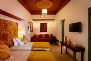 Habitación de hotel con 2 camas y sofá rojo en Riad les remparts de la kasbah en Marrakech