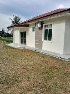 a small white house with a large yard at CASARIA HOMESTAY PD 3Bedrooms Bungalow House in Port Dickson