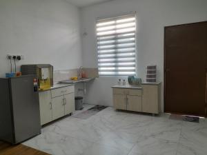 a kitchen with white walls and wooden cabinets and a window at CASARIA HOMESTAY PD 3Bedrooms Bungalow House in Port Dickson