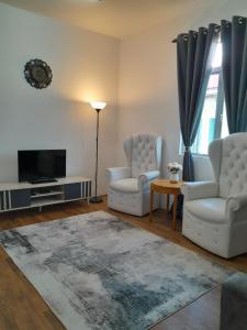 uma sala de estar com 2 cadeiras e uma televisão de ecrã plano em CASARIA HOMESTAY PD 3Bedrooms Bungalow House em Porto Dickson