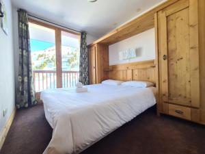 Un dormitorio con una cama grande y una ventana grande. en La cime des Arcs ARC 2000 Appartement 2 pieces en Résidence 4 étoiles, en Arc 2000
