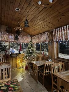 a restaurant with a christmas tree and wooden tables and chairs at Karczma Regionalna Młyn -pokoje gościne in Zwierzyniec