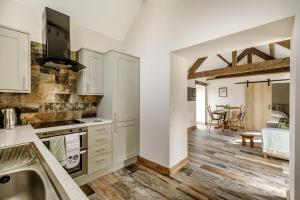 a kitchen with white cabinets and a wooden floor at Foxglove in Whitby