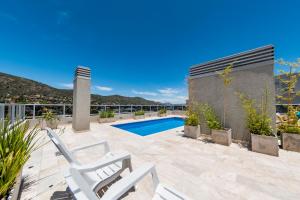 un patio con 2 sillas blancas y una piscina en Edificio Opera en Villa Carlos Paz - Pileta en Terraza e increíbles vistas en Villa Carlos Paz