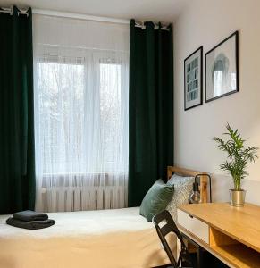 a bedroom with green curtains and a bed with a desk at Shape&Color premium Hostel in Warsaw