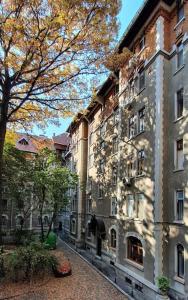 un edificio en una calle junto a un árbol en Sweet Dreams Suites Cosy Studio Piata Romana en Bucarest