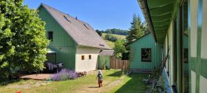 uma mulher em pé em frente a dois edifícios verdes em Altes Brauhaus Steinbach em Steinbach