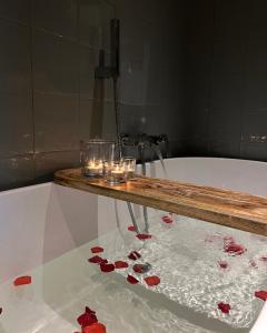 a bath tub with candles and red rose pedals at Logies aan de Dam in Middelburg