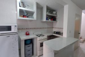cocina blanca con fogones y microondas en Casa Acá Diamante Gaviotas en Acapulco