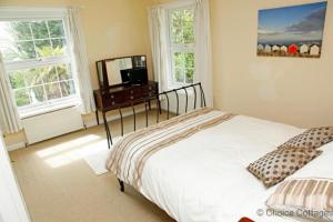 a bedroom with a bed and a desk and two windows at BISHOPS TAWTON OVERTON HOUSE 2 Bedrooms in Bishops Tawton