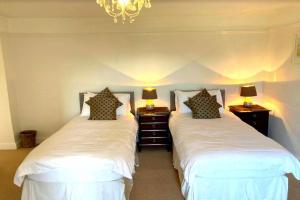 two beds in a bedroom with two lamps on tables at BISHOPS TAWTON OVERTON HOUSE 2 Bedrooms in Bishops Tawton