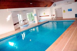 ein großes Schwimmbecken mit blauem Wasser in einem Gebäude in der Unterkunft PUTSBOROUGH CLIFTON COURT 17 1 Bedroom in Croyde