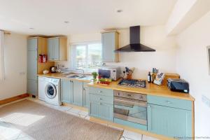 cocina con armarios azules y lavadora en VALLEY VIEW 2 Bedrooms, en High Bickington