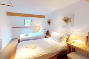 1 Schlafzimmer mit 2 Betten und einem Schreibtisch mit einer Lampe in der Unterkunft BUCKLAND BREWER COB BARN 2 Bedrooms in Buckland Brewer