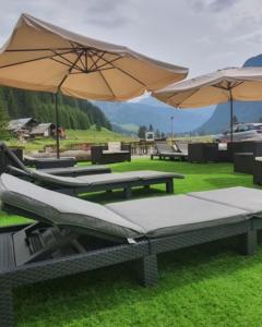 eine Gruppe Picknicktische mit Sonnenschirmen auf dem Rasen in der Unterkunft Soggiorno Dolomiti in Mazzin