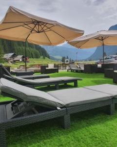 a group of picnic tables with umbrellas on the grass at Soggiorno Dolomiti in Mazzin
