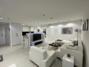 a living room with white furniture and a tv at Lovely new apartment by the Parliament in Budapest