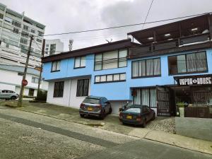 due auto parcheggiate di fronte a un edificio blu di Casa Azul a Manizales