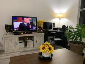 a living room with a television and a table with flowers at Pearlridge Gardens and Tower Aiea, Hawaii 96701 in Aiea